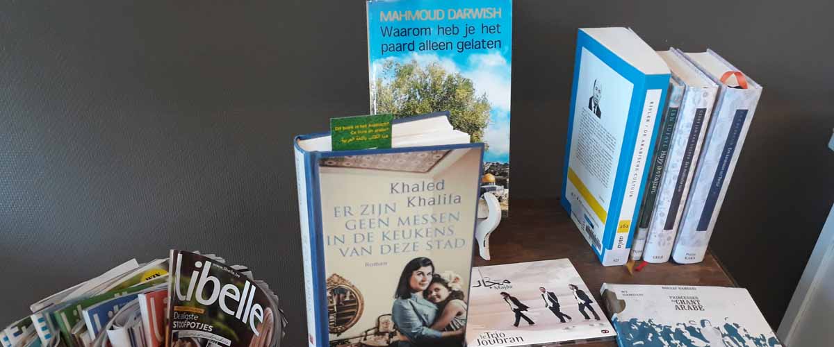 Arabische boeken staan uitgestald op een tafeltje, met de Libelle en andere Nederlandstalige tijdschriften ernaast.